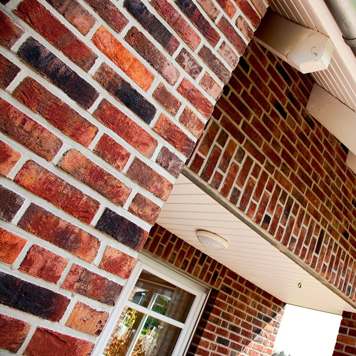 Red brick building exterior with white trim and a window.