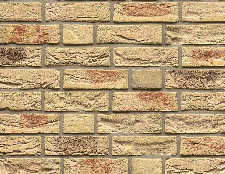 Close-up of a brick wall with varied tan, beige, and reddish-brown bricks and grey mortar.