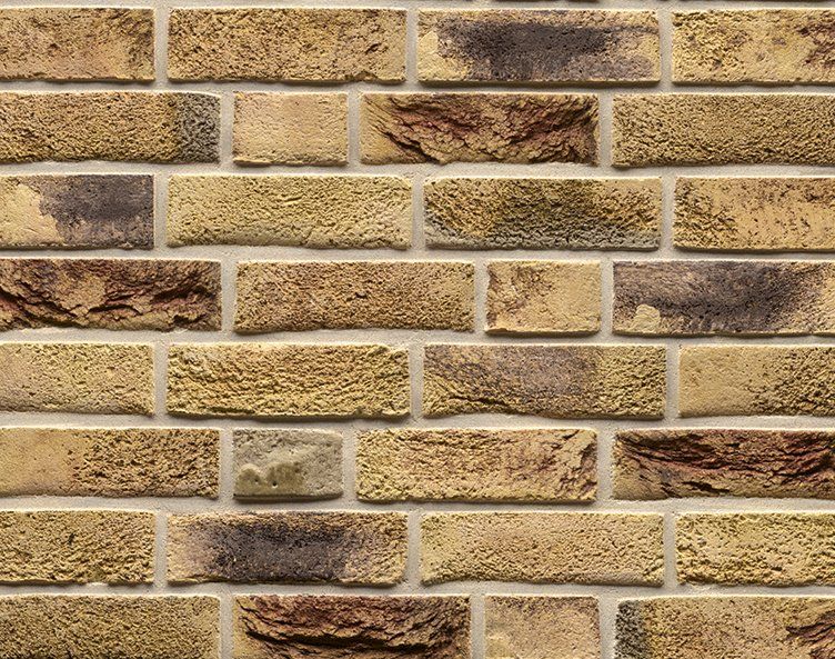 Close-up of a brick wall with tan and brown bricks and lighter mortar.