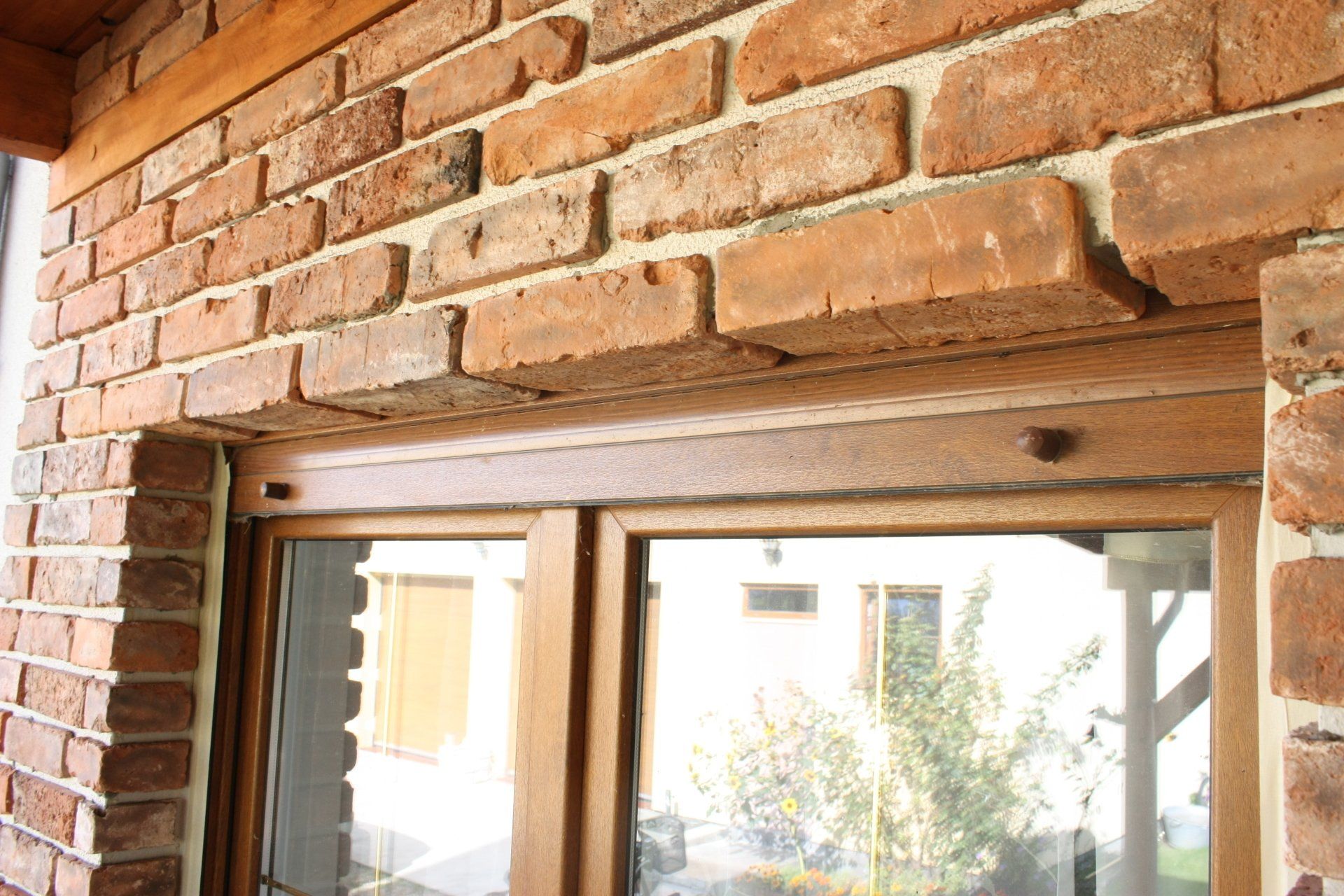 Brick facade with a wooden window frame. Red brick walls and a brown wooden window.