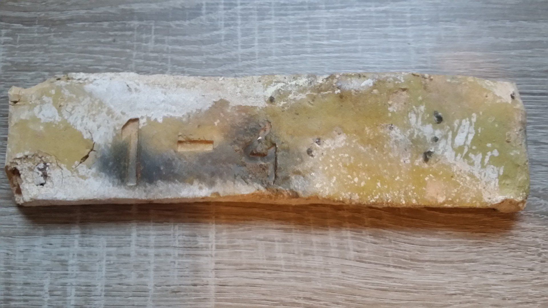 Brick with weathered appearance, various colors: yellow, black, and white.