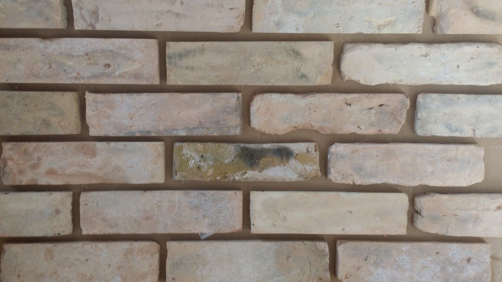 Tan and cream brick wall with dark mortar.
