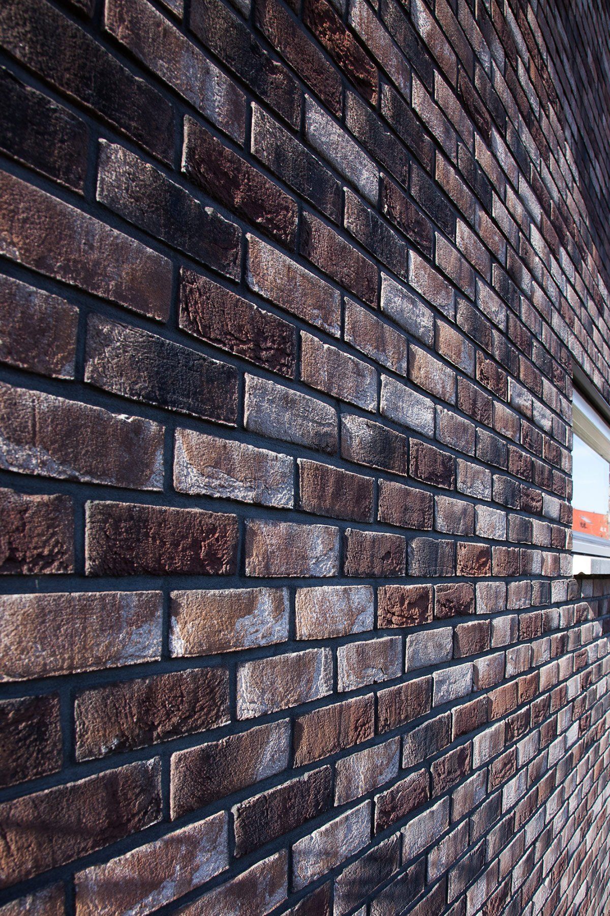 Brick wall exterior, varied dark brown tones, black mortar. Angled perspective.