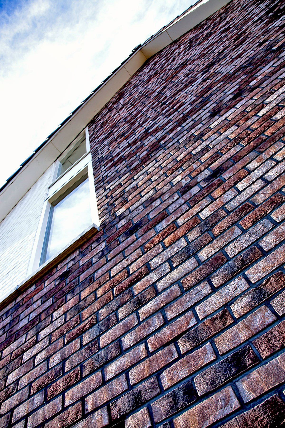 Brick wall with a window against a blue sky.
