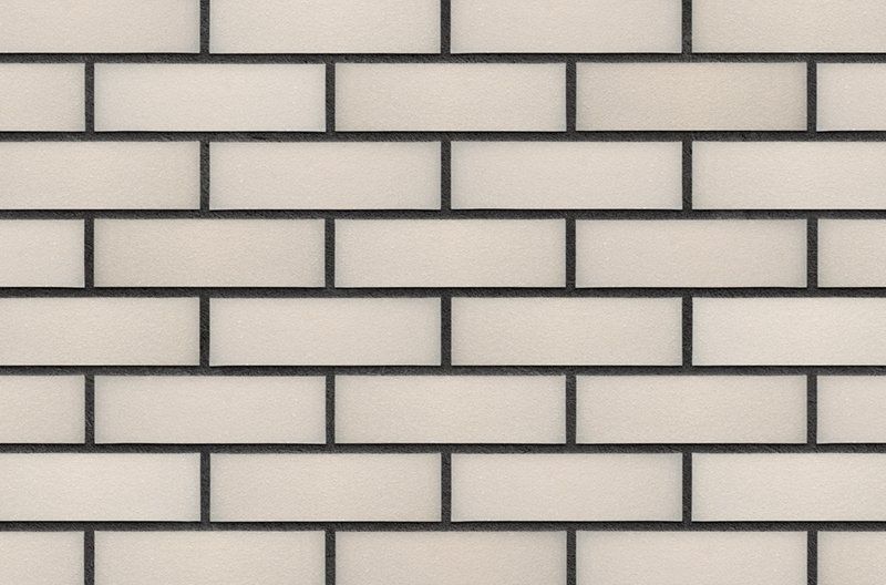 Off-white brick wall with dark gray grout.