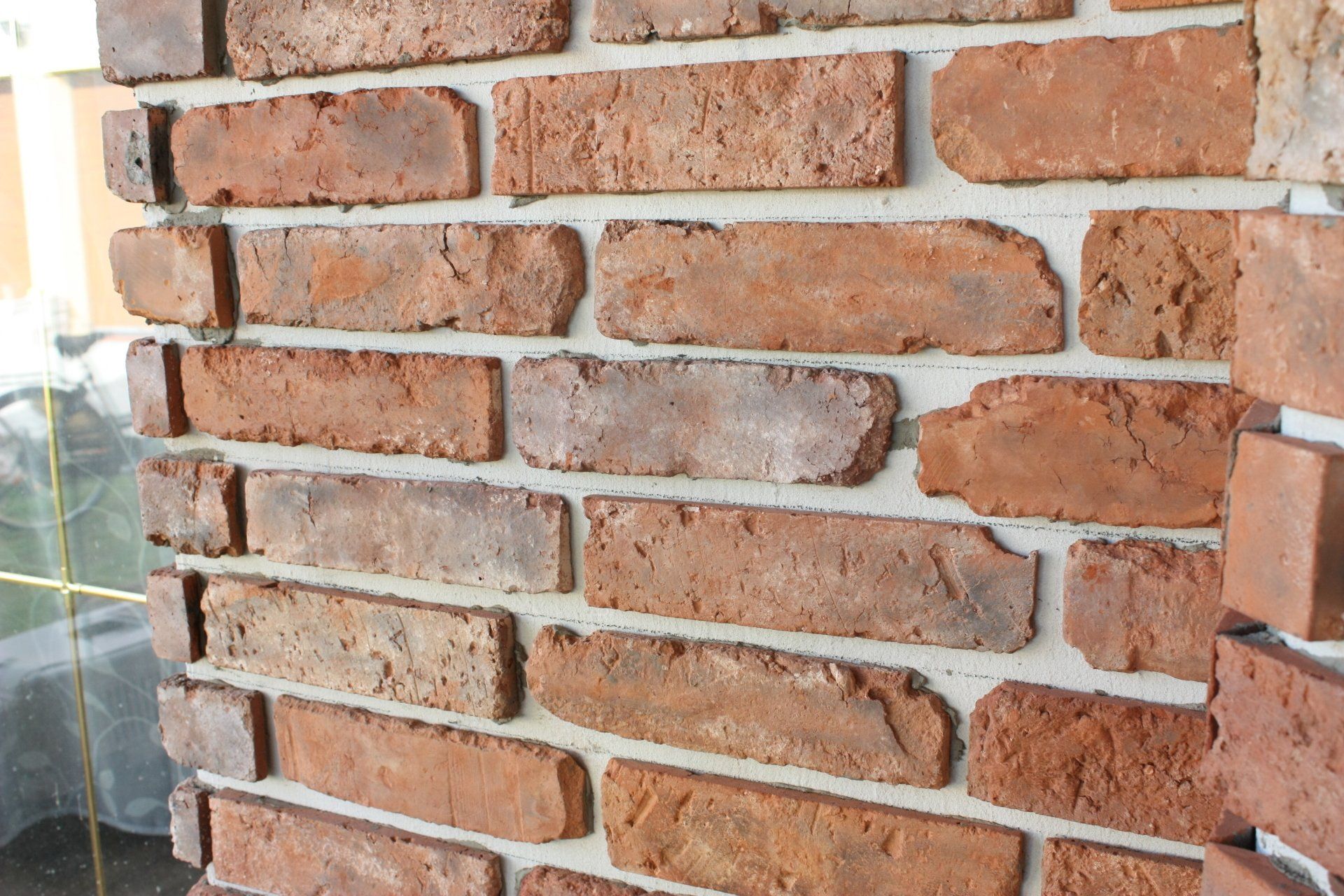 Close-up of a brick wall with varied reddish-brown bricks and gray mortar.