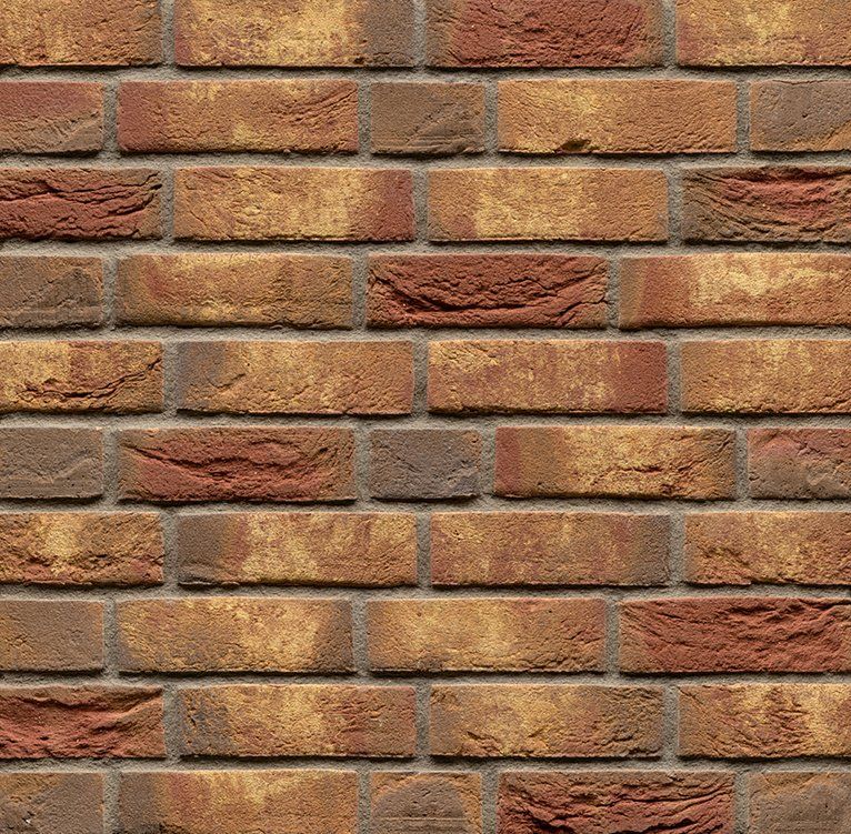 Close-up of a brick wall with varying shades of red, orange, and brown, with gray mortar.