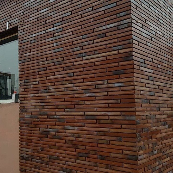Exterior brick wall corner, red-brown, with a window and a lighter-colored, smooth wall to the left.