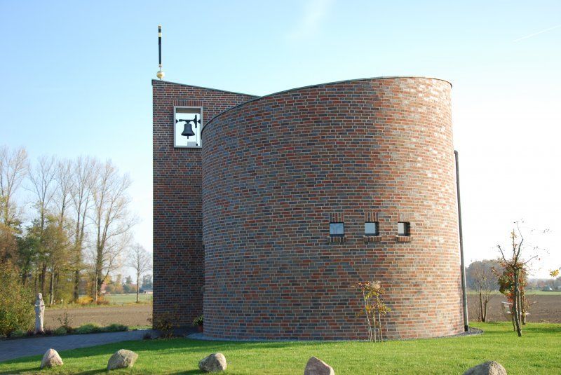 Brick church with a cylindrical main section and a rectangular bell tower.