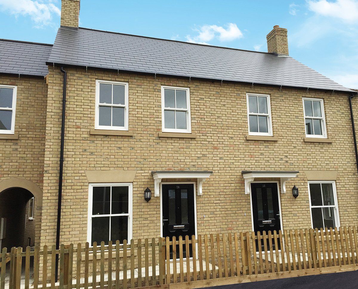 Stone row houses with black doors, white windows, and wooden fences.