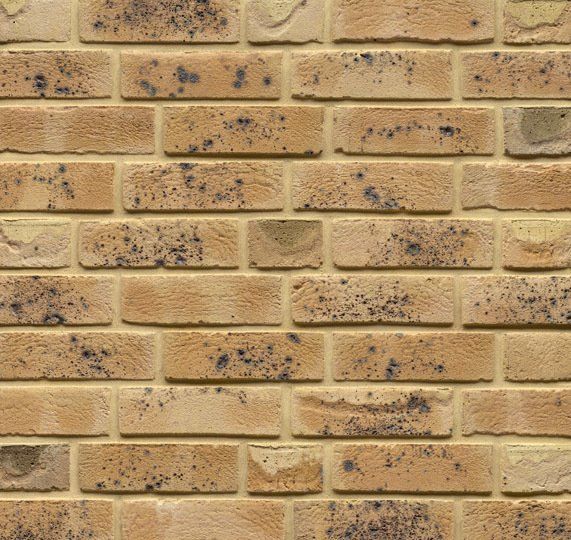 Yellow and brown brick wall with dark spots.