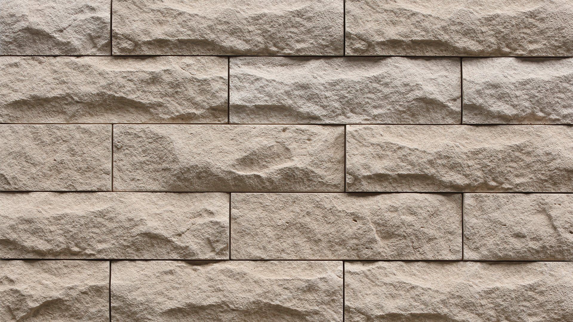 Beige and gray brick wall with textured, uneven surfaces.