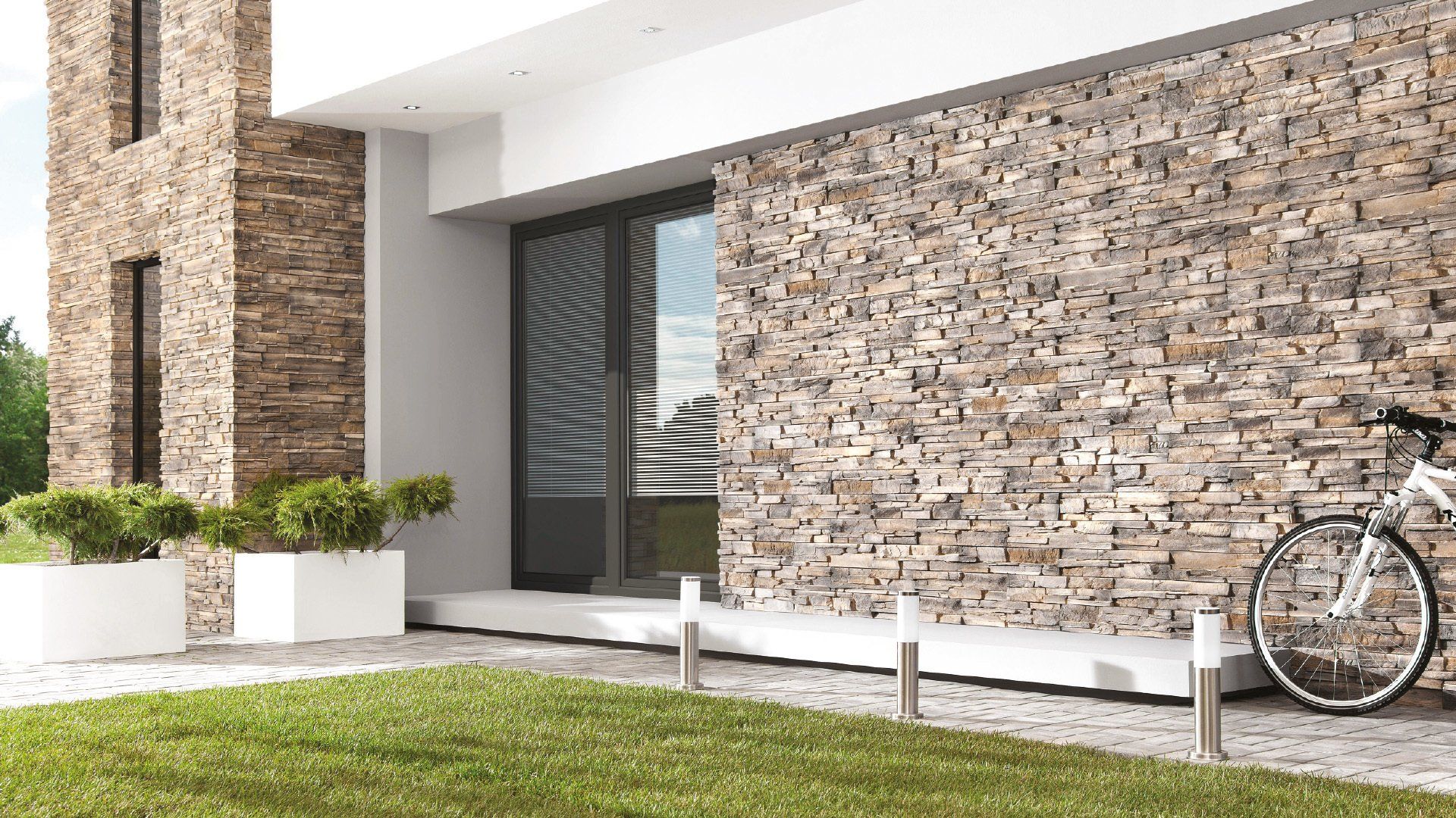 Modern home exterior with stone wall, glass door, bike, and white planters.