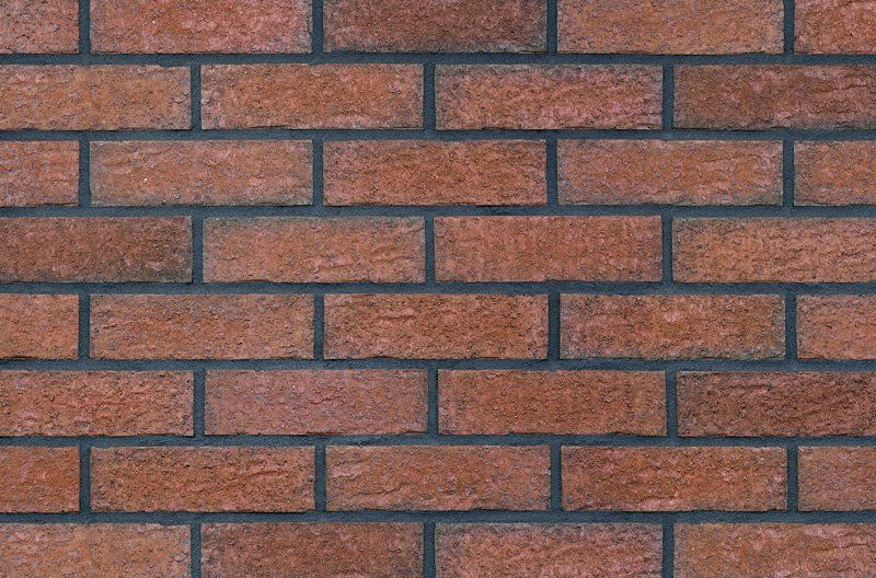 Brick wall with reddish-brown bricks and dark gray mortar joints.