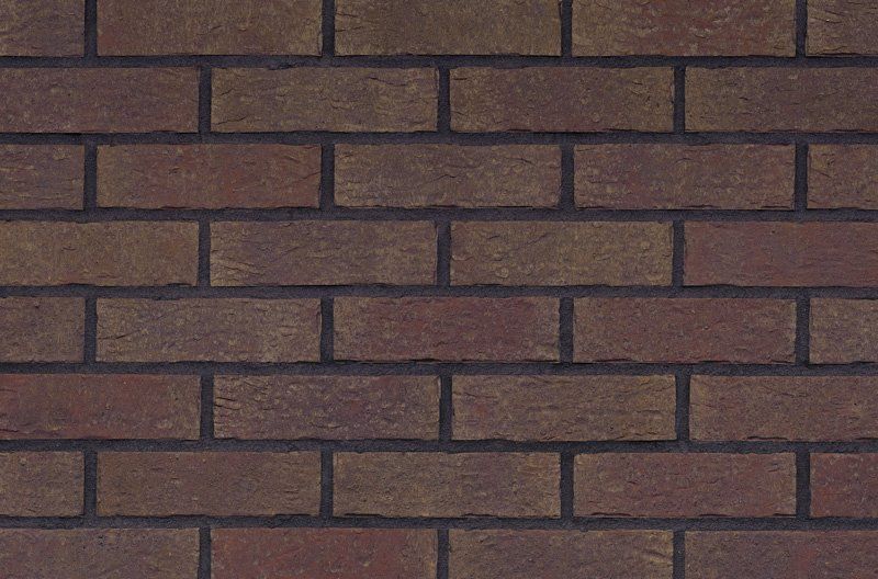 Close-up of a brick wall with dark brown bricks and dark gray mortar.