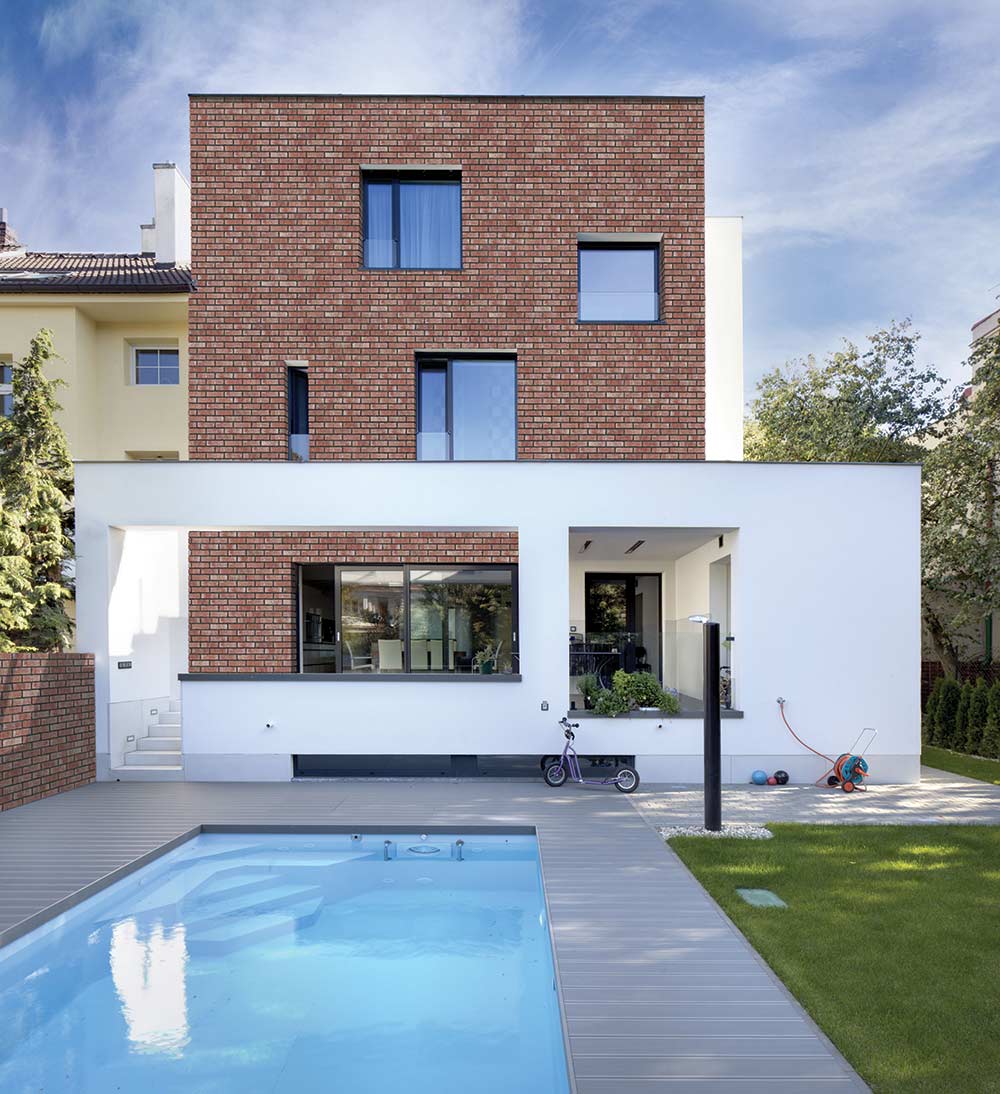 Modern home with brick facade, white accents, and a pool.