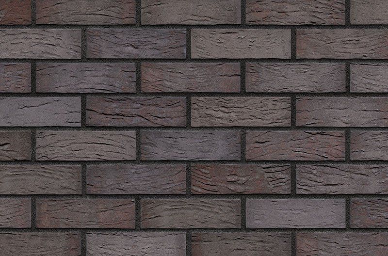 Brick wall with dark brown bricks and dark gray mortar.