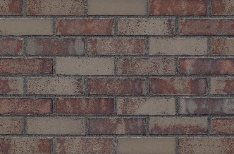 Brick wall with alternating rows of light tan and reddish-brown bricks.