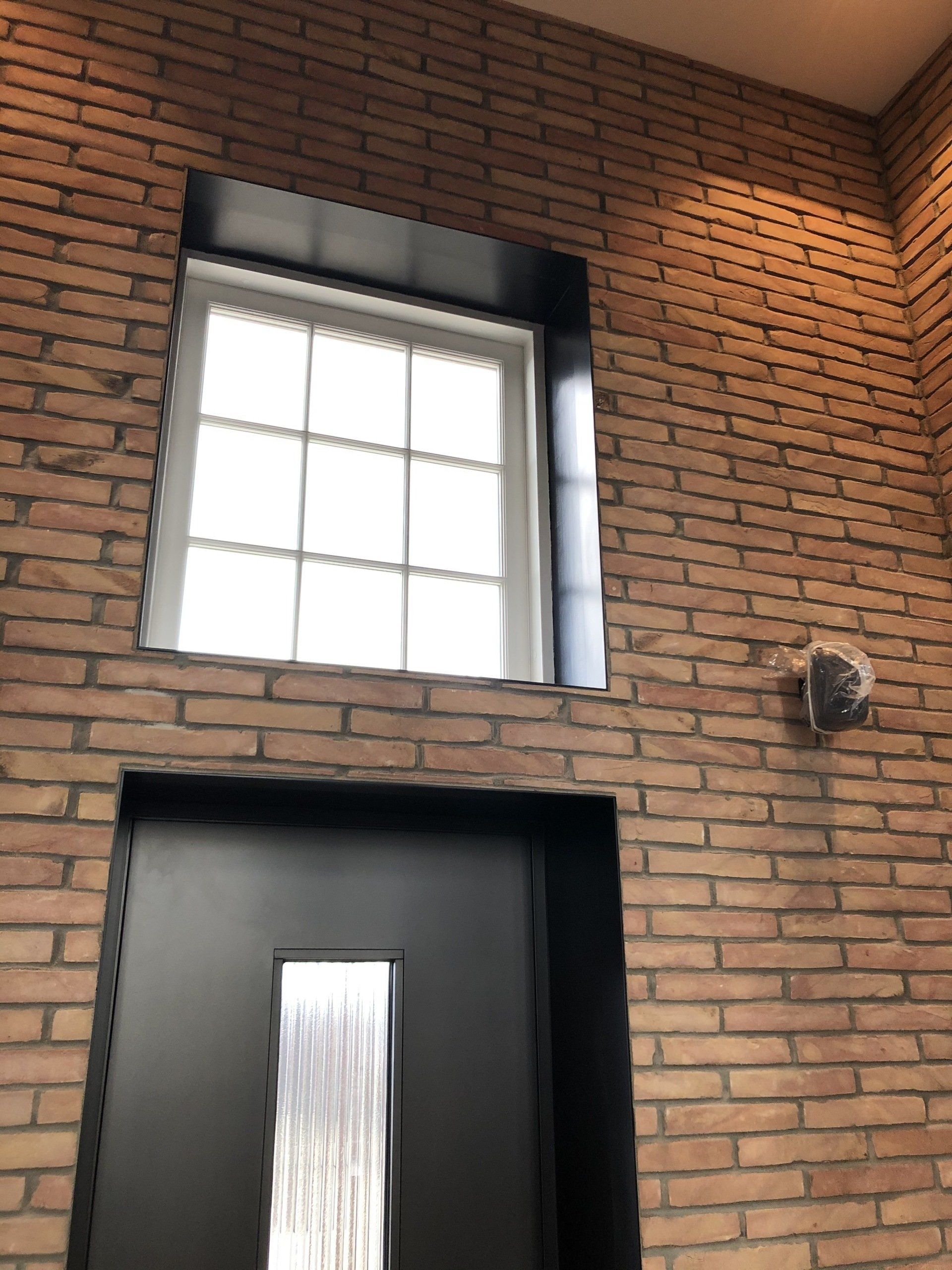 Brick wall with a window and door, both with black frames.