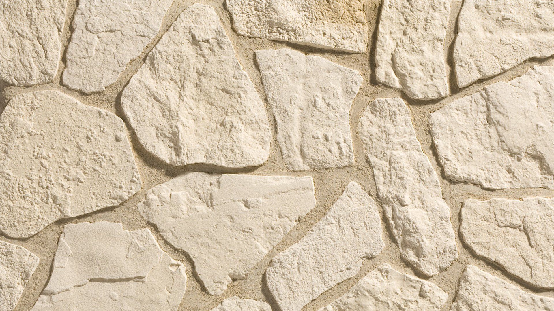 Close-up of a wall made of irregularly shaped, light-beige stones with tan grout.