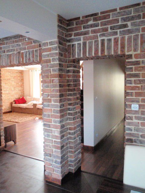 Brickwork interior doorway with dark wood floors and view of a living room.