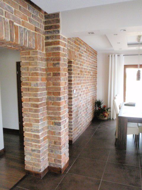 Interior with brick accent wall and columns, brown tile floor, white ceiling, and a dining area.