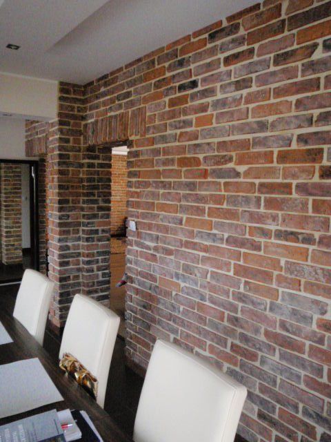 Brick accent wall in a dining room, with white chairs, and a glimpse of a doorway.