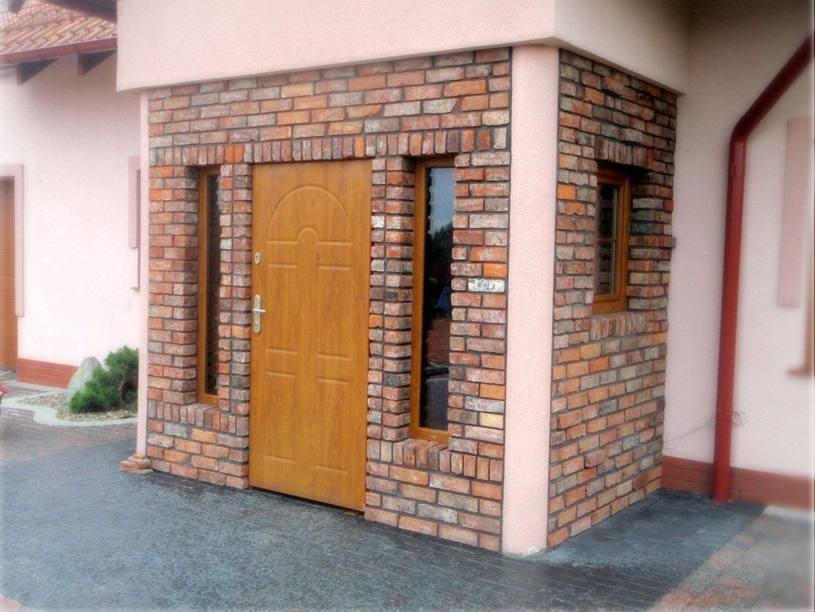 Exterior of a building with a brick facade and wooden door and windows.