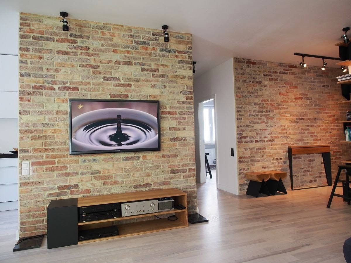 Living room with brick wall, TV, and entertainment center; track lighting.
