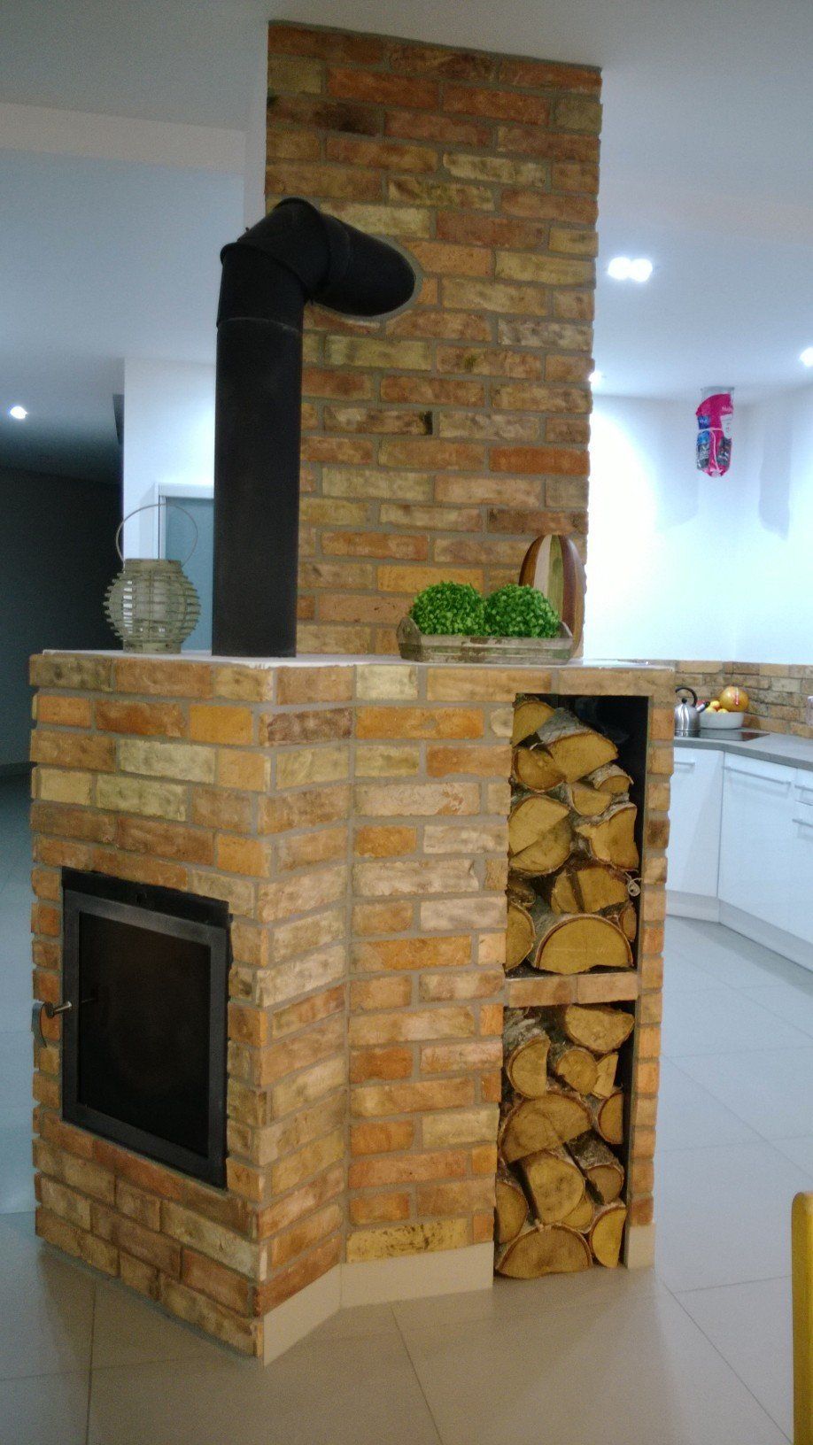 Brick fireplace with firewood storage and black chimney.