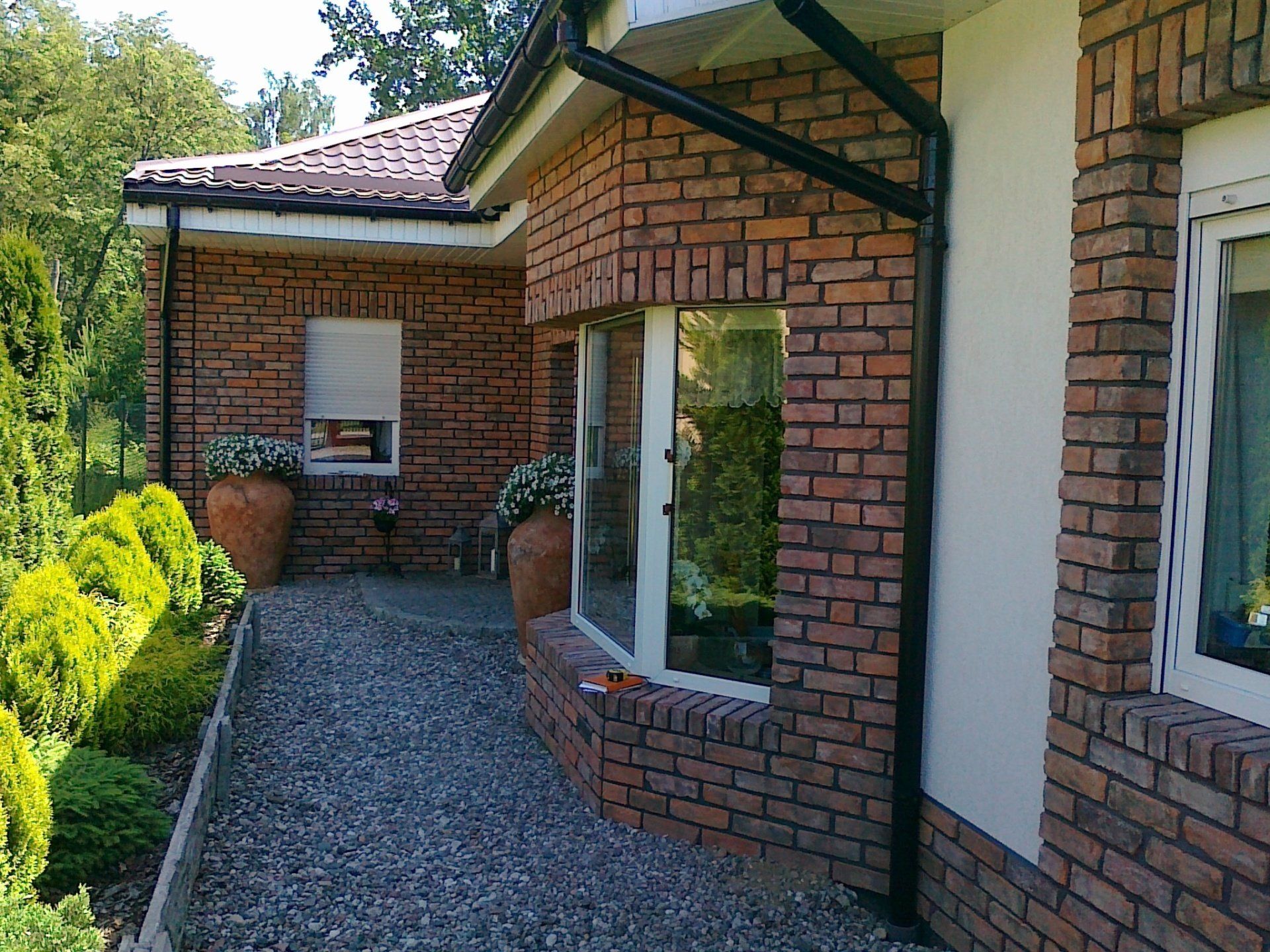 Brick house exterior with a walkway, windows, and greenery.