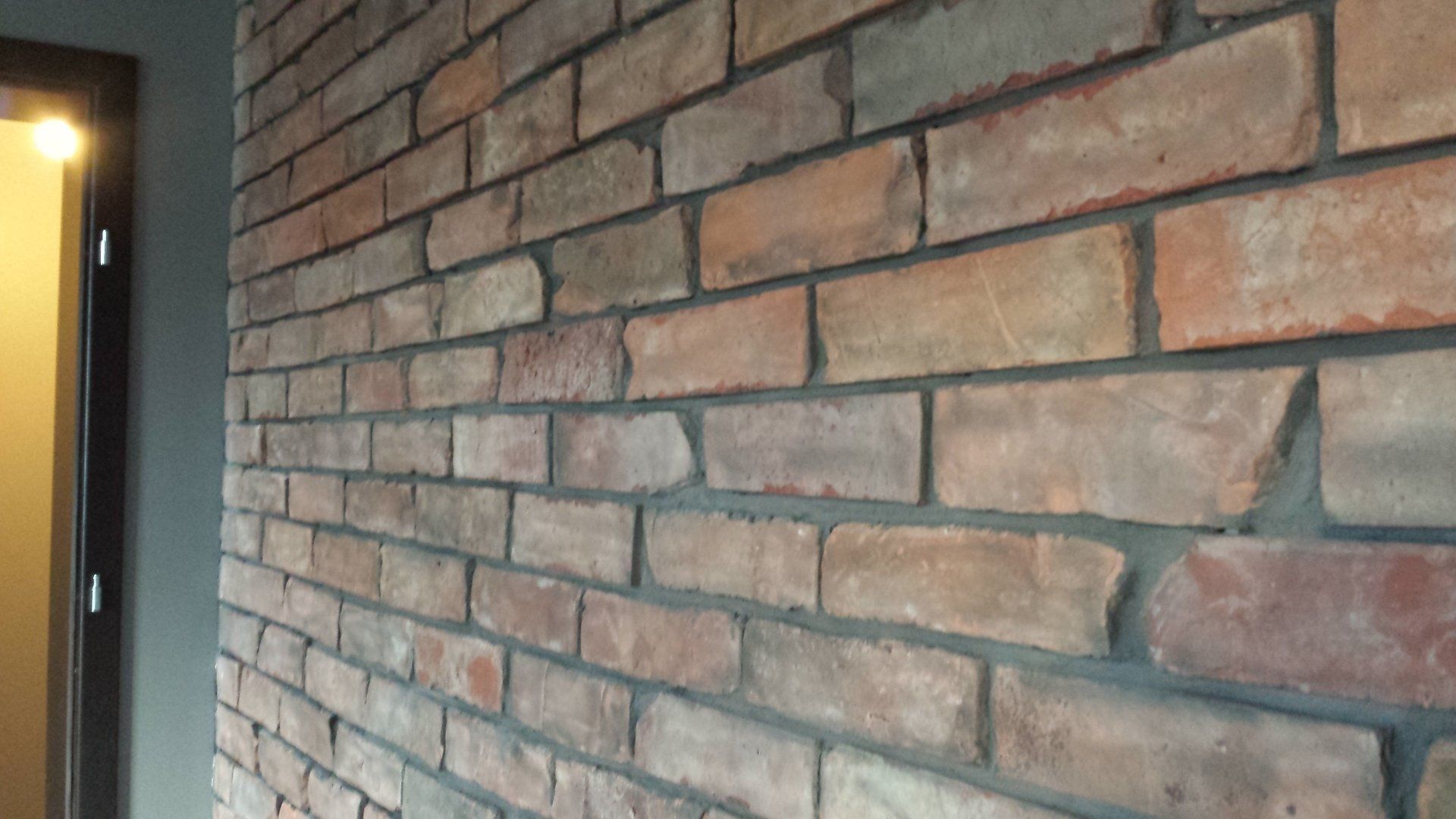 Brick wall in shades of red and brown, with dark gray mortar.