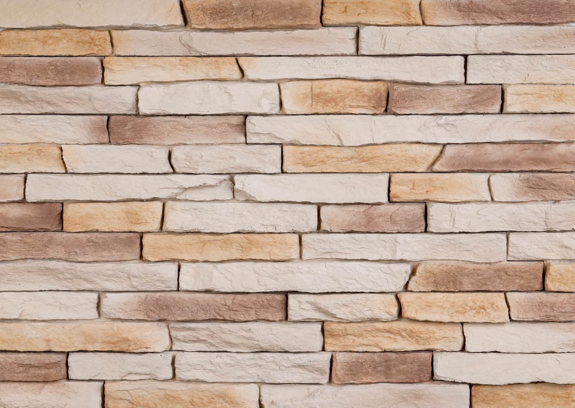 Close-up of a brick wall with varying shades of tan, brown, and beige, arranged in a horizontal pattern.