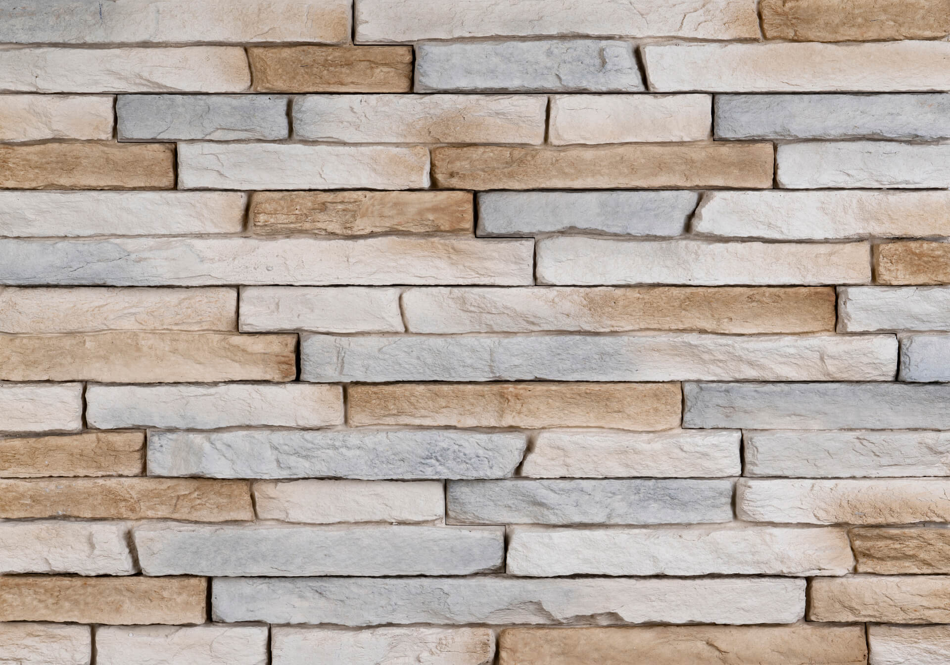 Stone wall with layered, rectangular blocks in shades of beige, gray, and brown.