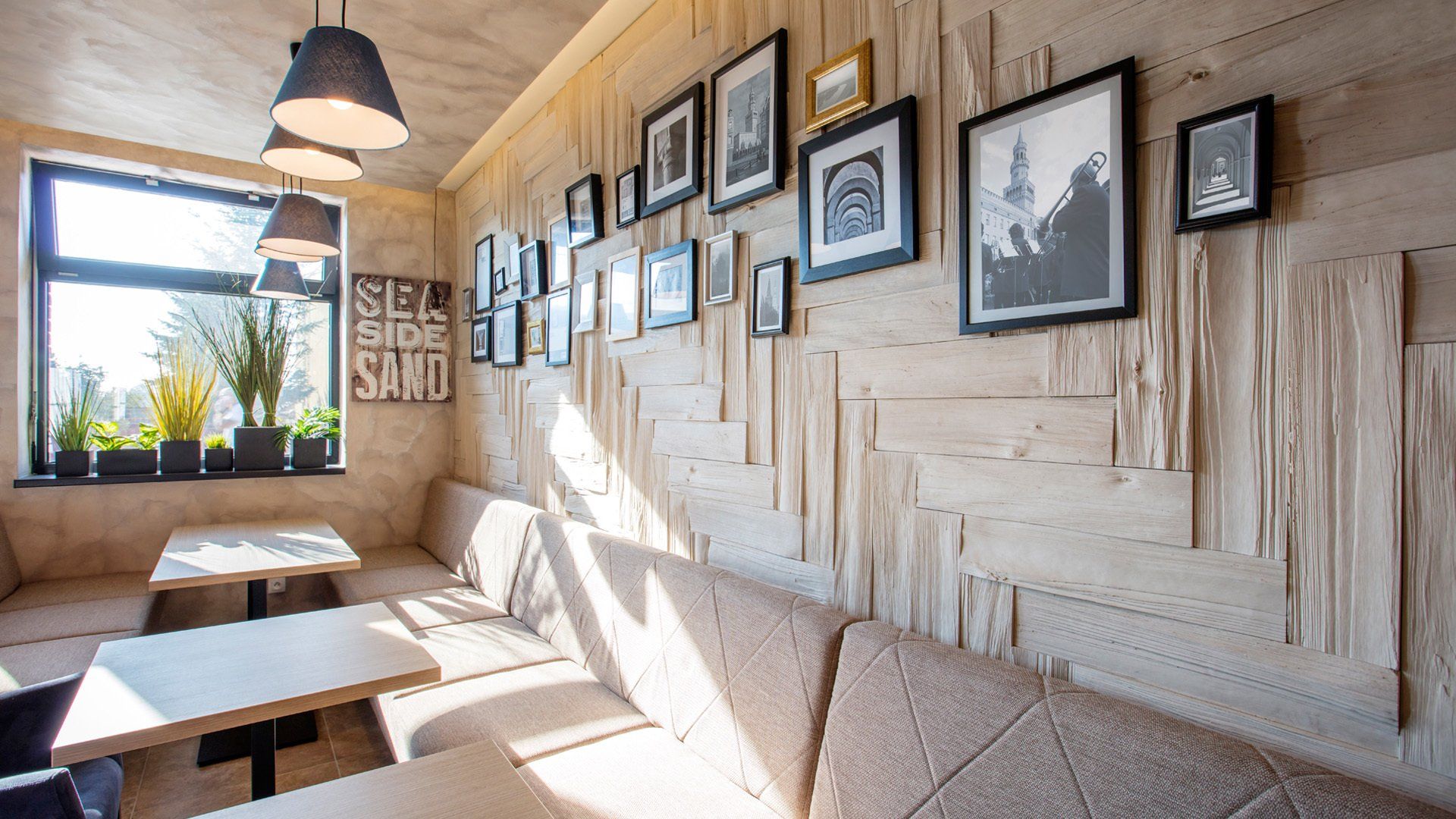 Interior of a cafe with wood-paneled walls, a window, tables, and framed artwork.