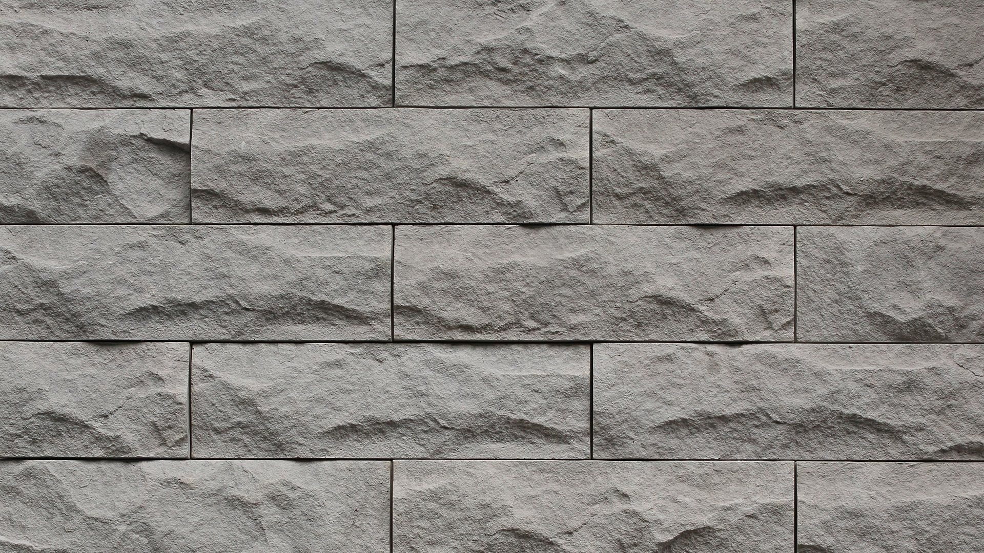 Gray, textured brick wall with rough surface.