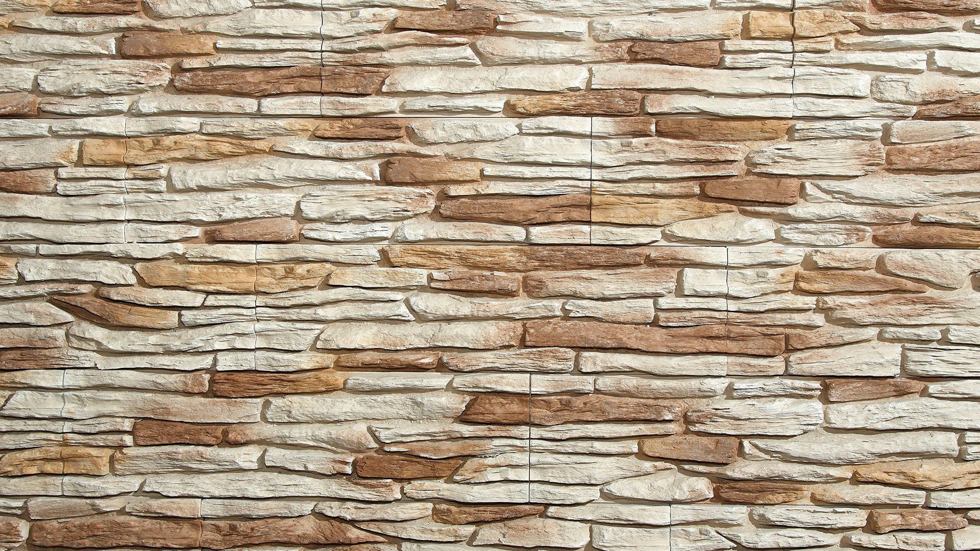 Stone brick wall with tan, brown, and cream-colored rectangular blocks.