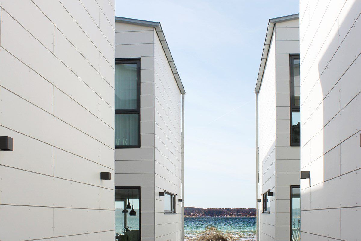 Two white buildings frame a view of the ocean and sky.