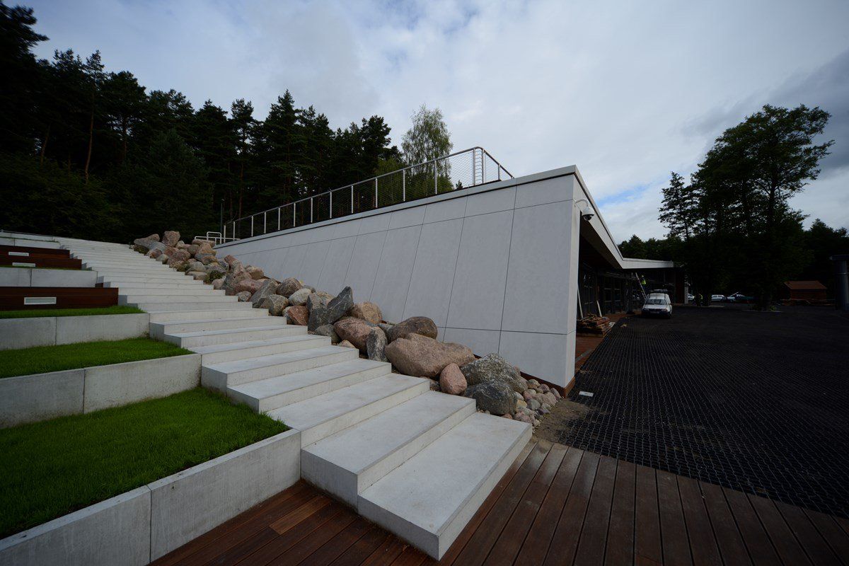 White building with stone steps leading up hillside. Gravel and wooden deck.