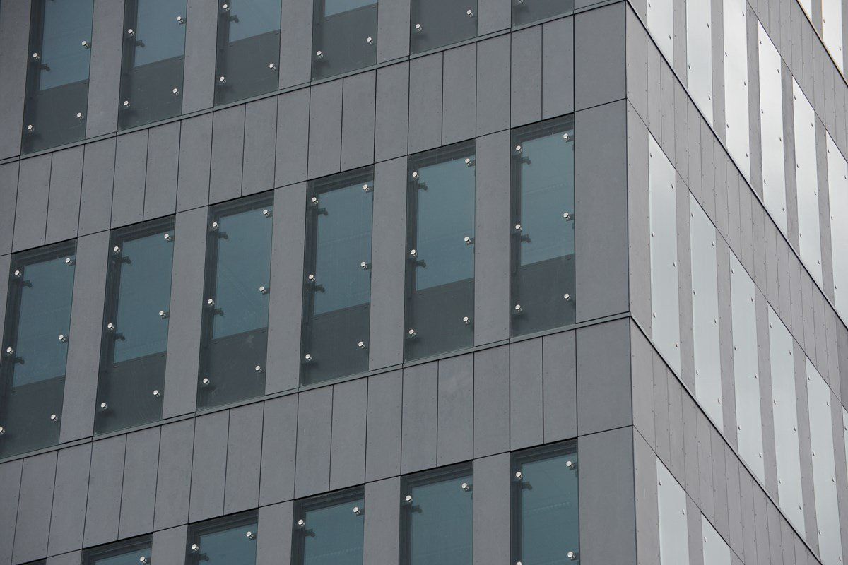 Gray modern office building exterior with reflective windows.