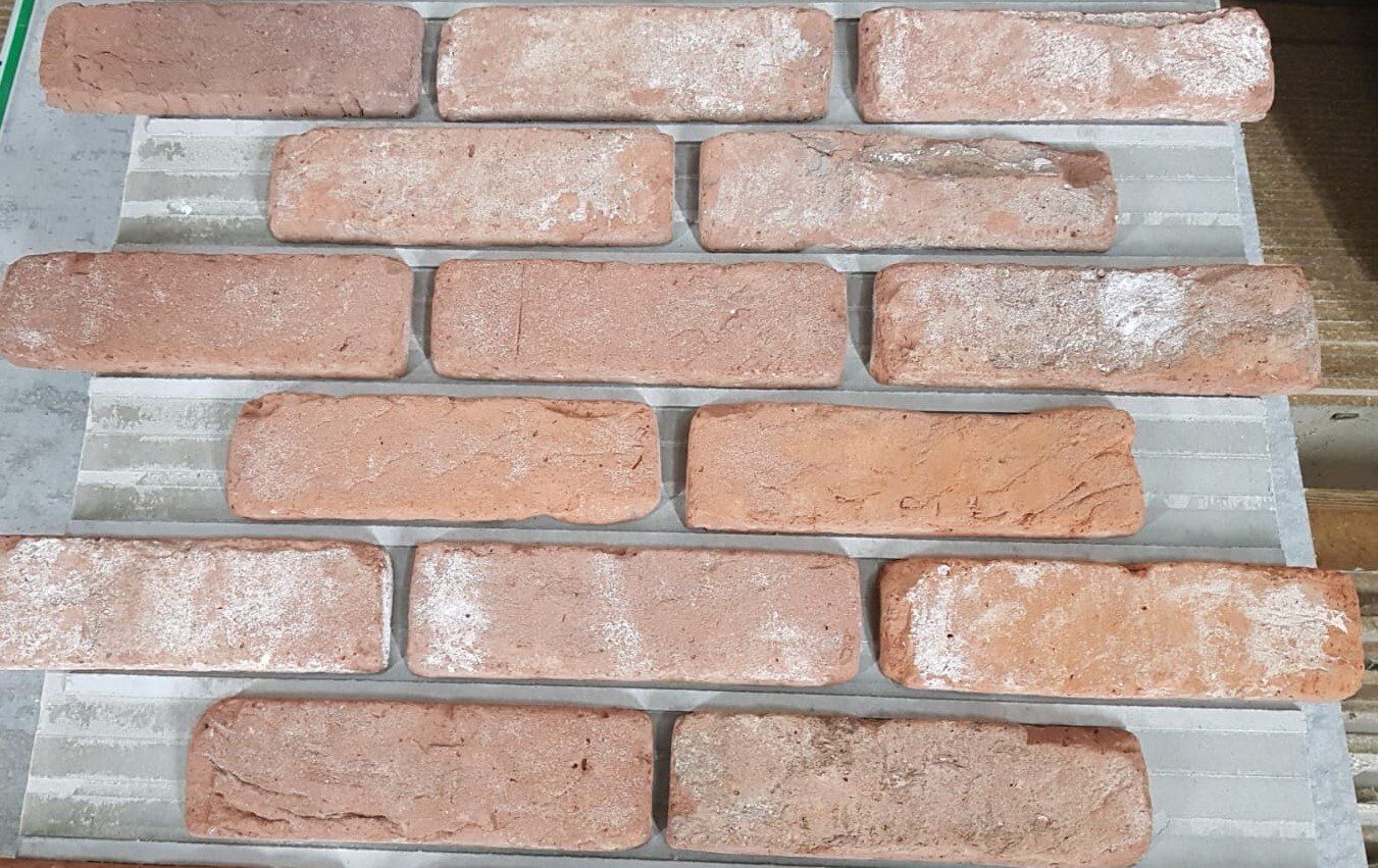 Rows of red bricks with white residue on a gray surface.