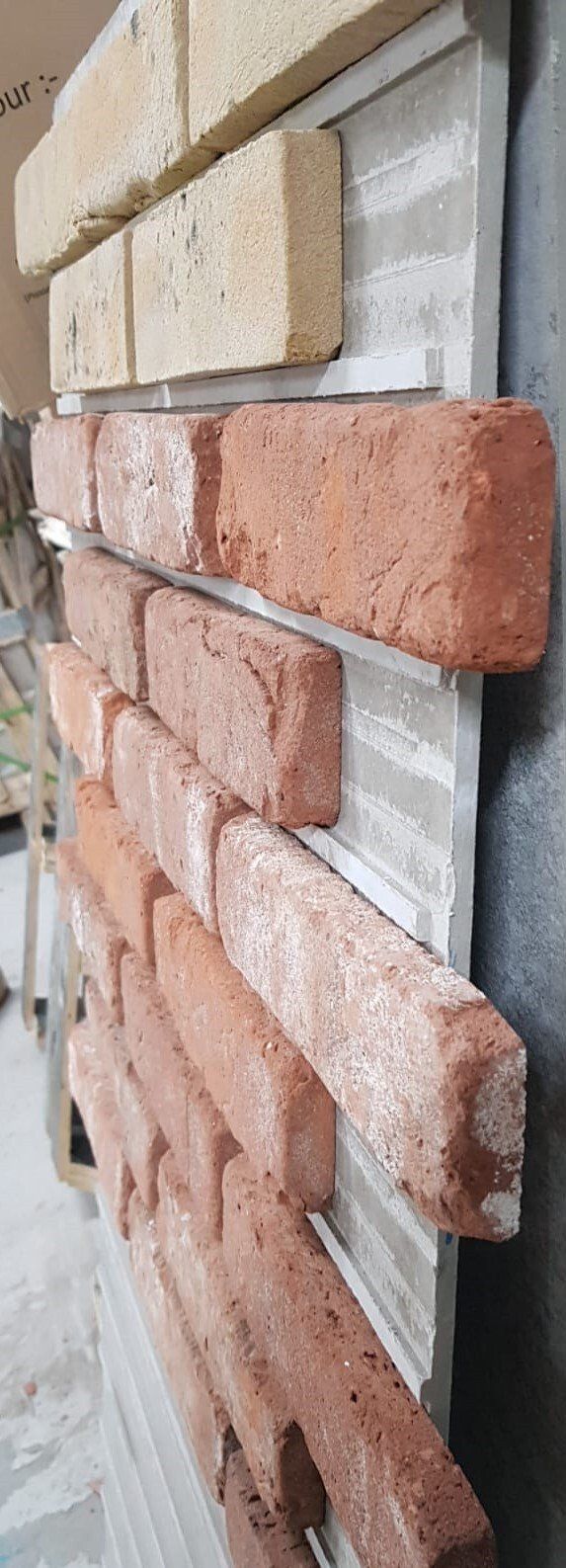 Close-up of brick veneer panels, showing red and cream-colored bricks arranged in a running bond pattern.