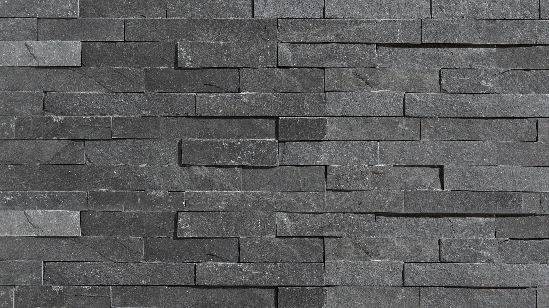 Dark gray stone wall with a layered, textured pattern.