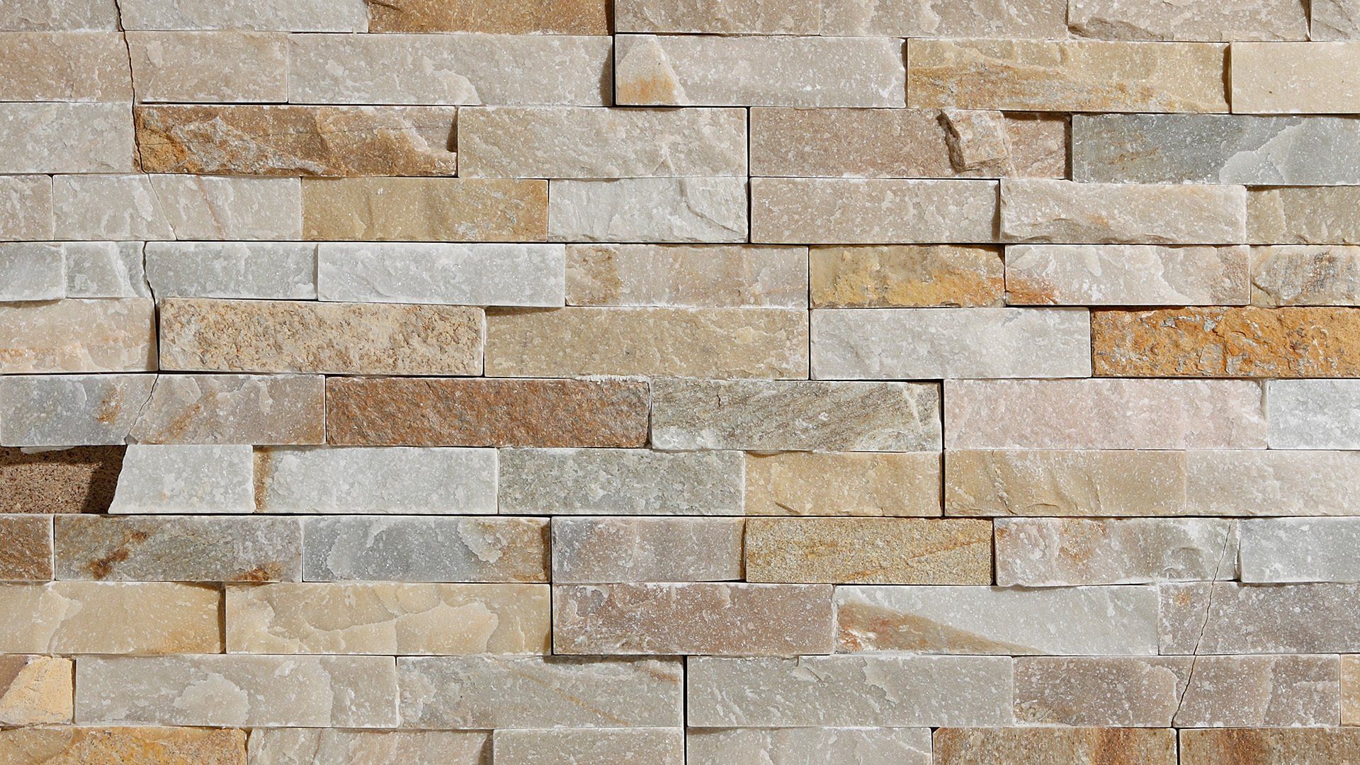 Close-up of a stacked stone wall with tan, gold, and gray rectangular pieces.