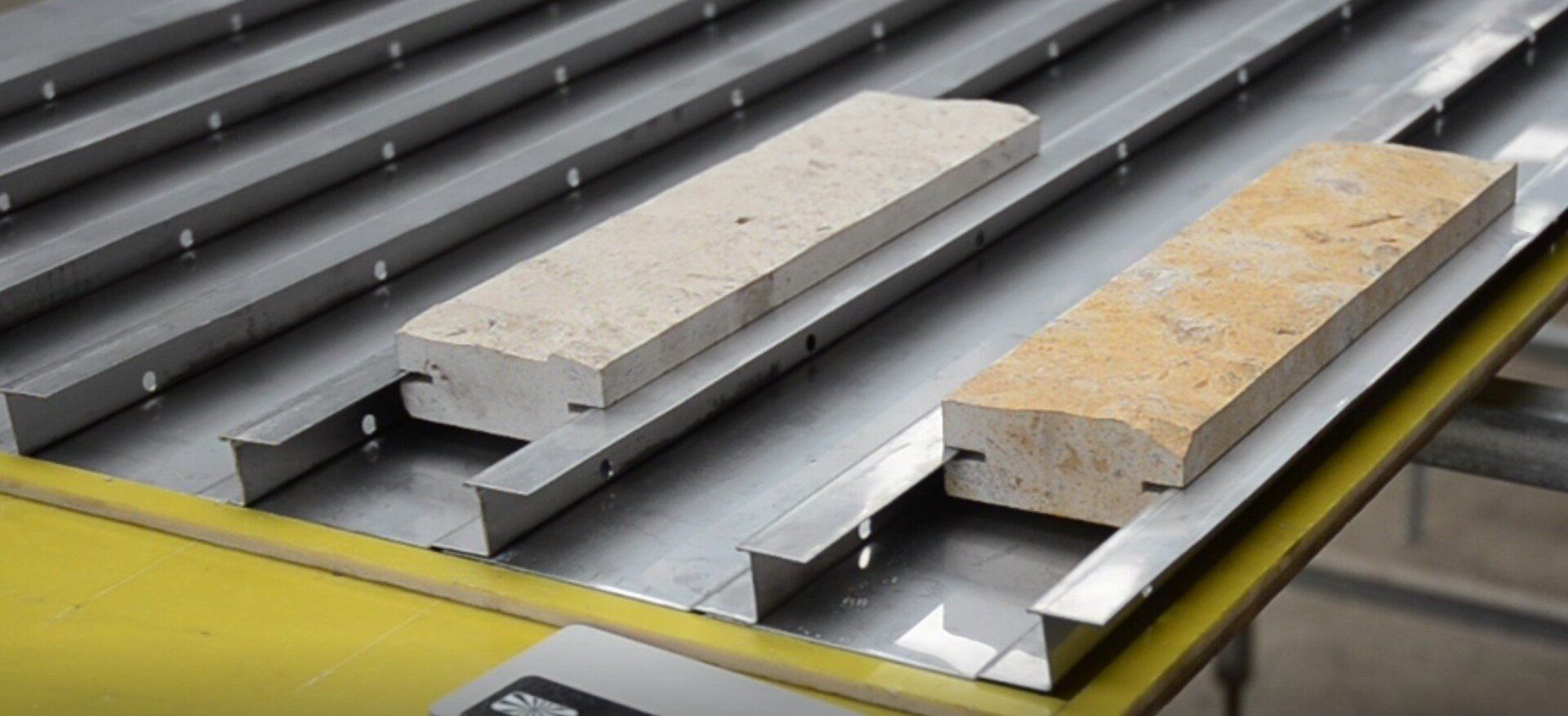 Two rectangular stone blocks on a metallic conveyor system.