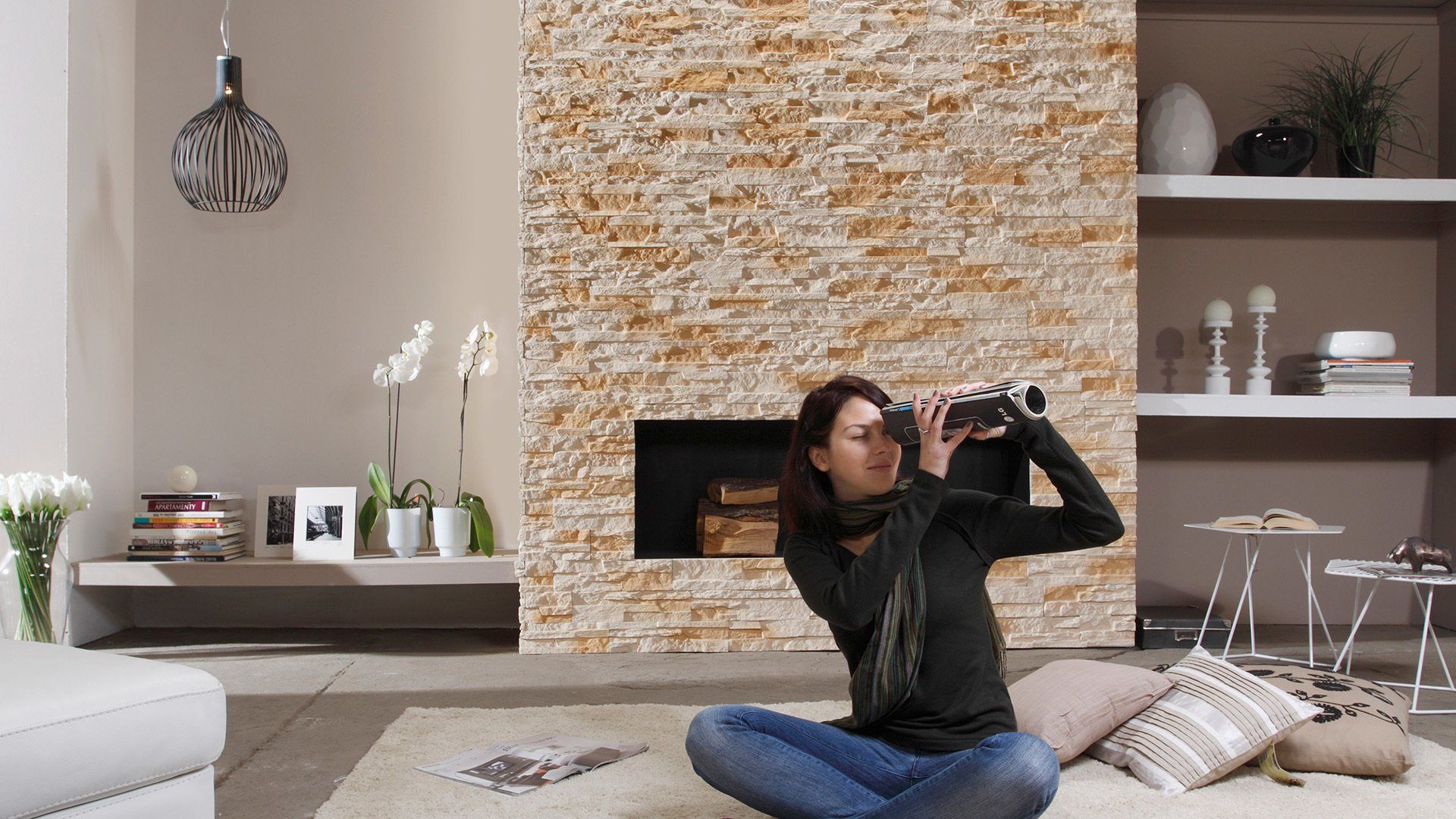 Woman taking photo in living room with stone fireplace.
