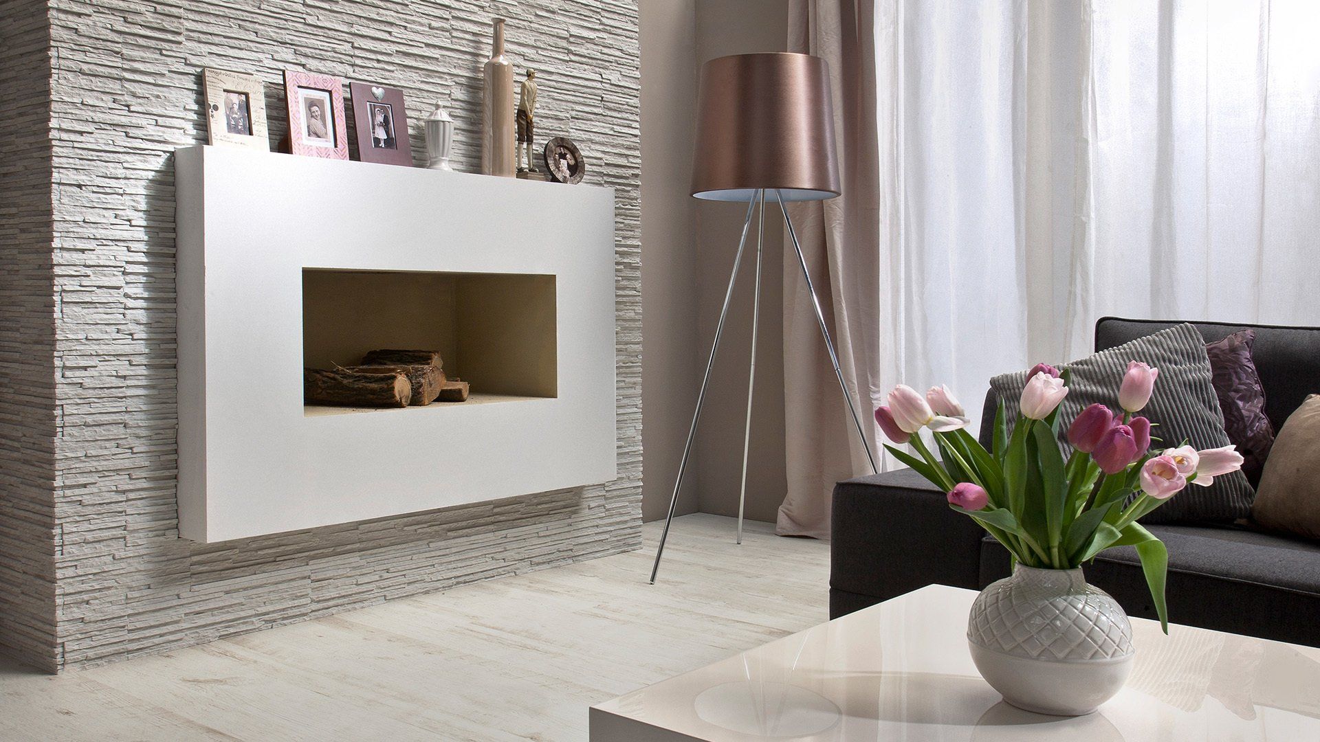 Modern living room with fireplace, white table, flowers, and floor lamp.