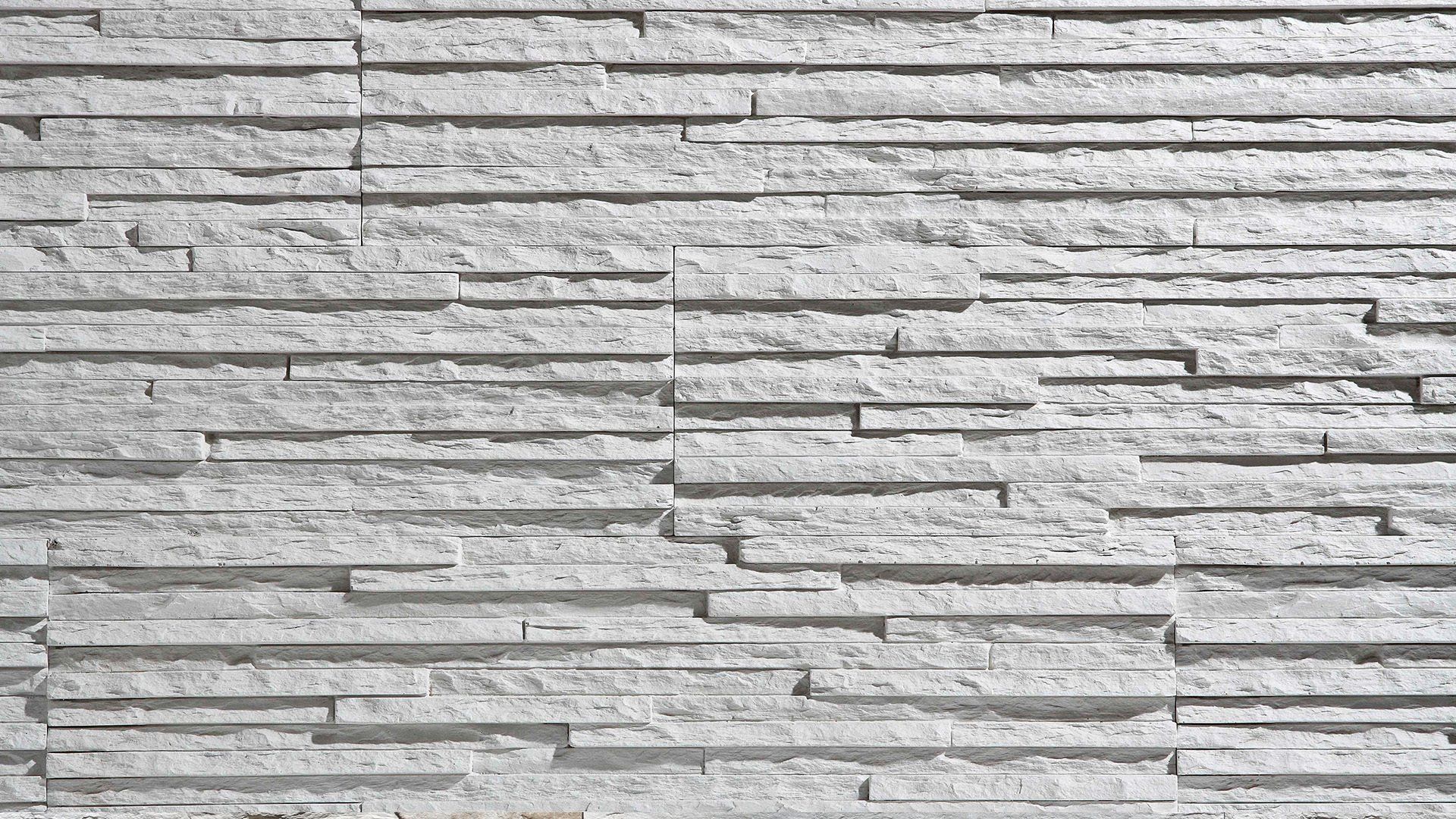 Textured, light-grey stone wall with horizontal, uneven rows.