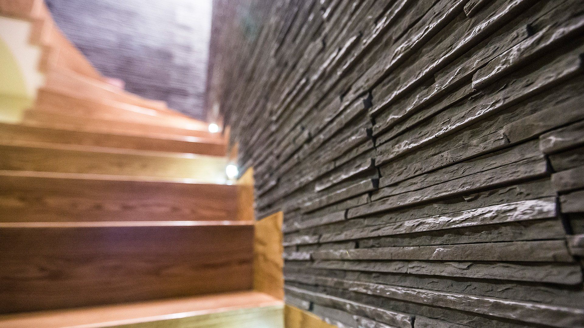 Stone wall detail next to wooden staircase; natural light.