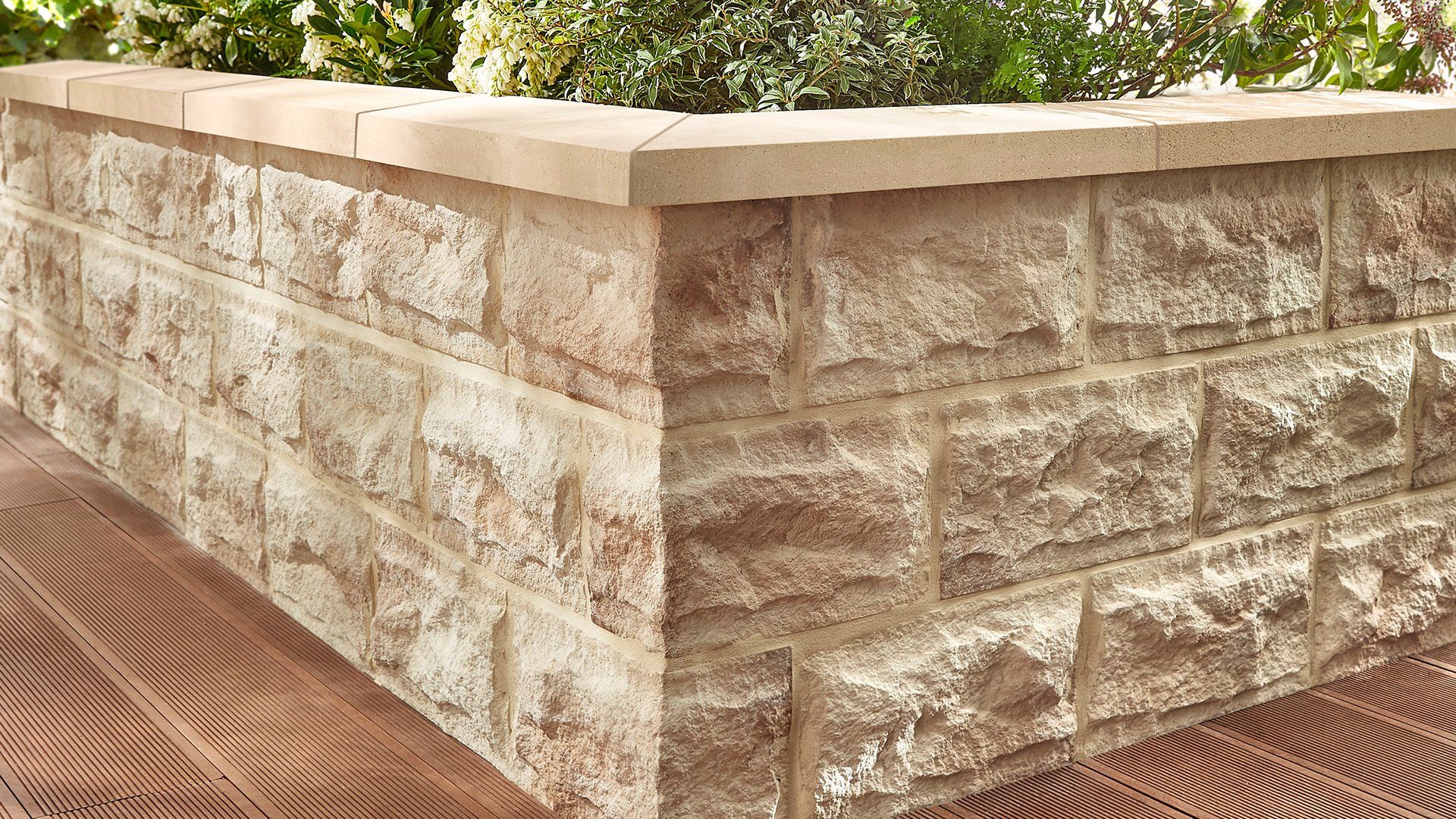 Stone retaining wall with plants on top.